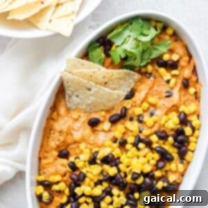 Street corn and queso dip in a white bowl with black beans.