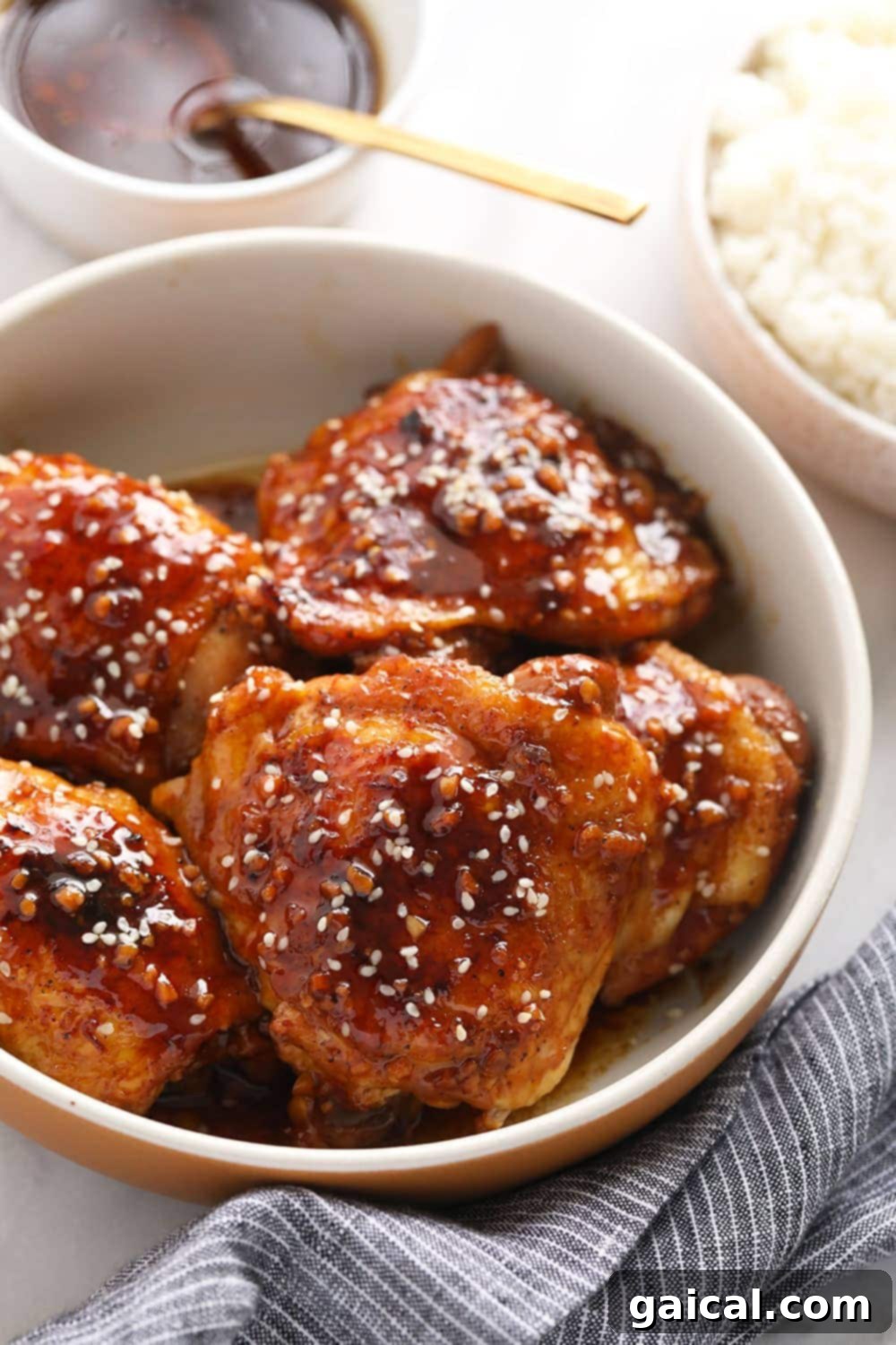 The ultimate sticky, sweet Instant Pot Honey Garlic Chicken Thighs recipe. Sticky, sweet honey garlic Instant Pot chicken thighs served in a bowl, garnished with sesame seeds.