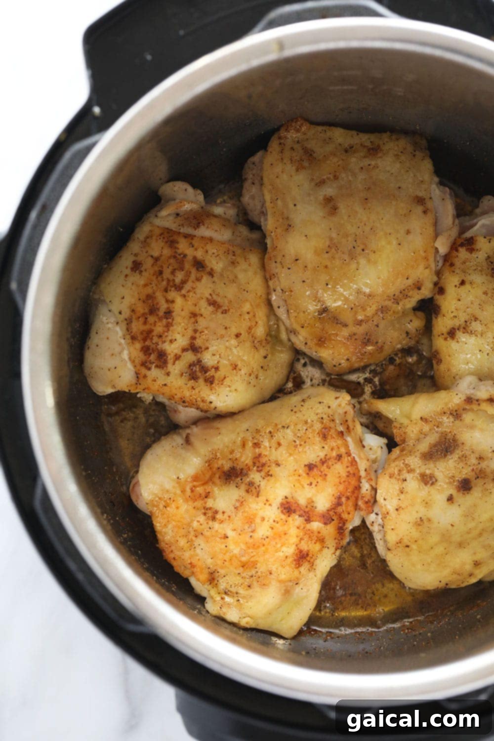 Searing chicken thighs in the Instant Pot for maximum flavor. Chicken thighs searing in an Instant Pot, developing a golden-brown crust.