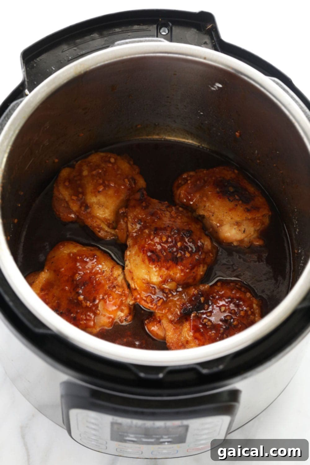 Cooked honey garlic chicken thighs in the Instant Pot. A batch of honey garlic chicken thighs resting in the Instant Pot after cooking, coated in sauce.