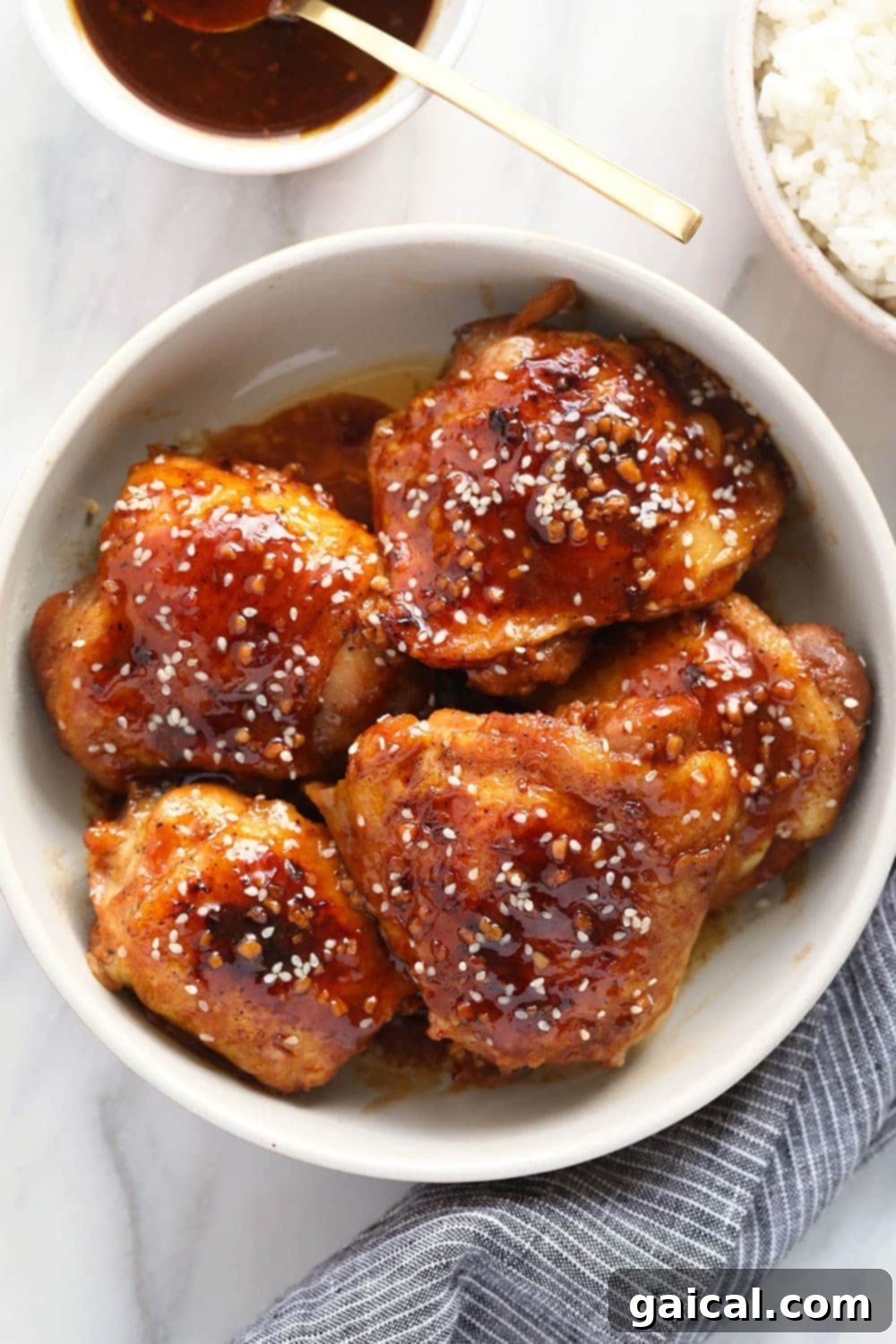 Delicious honey garlic chicken thighs ready to be served. A serving of Instant Pot honey garlic chicken thighs in a bowl, garnished with fresh scallions and sesame seeds.