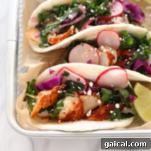 Three fish tacos with kale and radishes on a tray, ready to be served.
