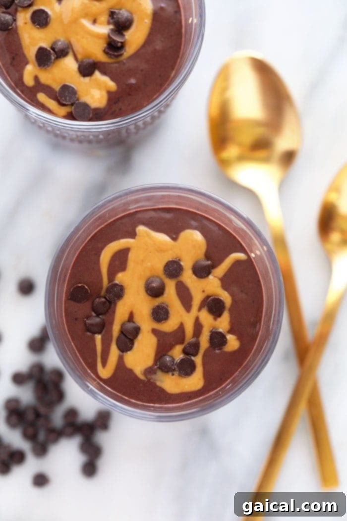A delectable chocolate protein shake generously topped with a rich drizzle of almond butter and a scattering of dark chocolate chips, creating an irresistible visual appeal.