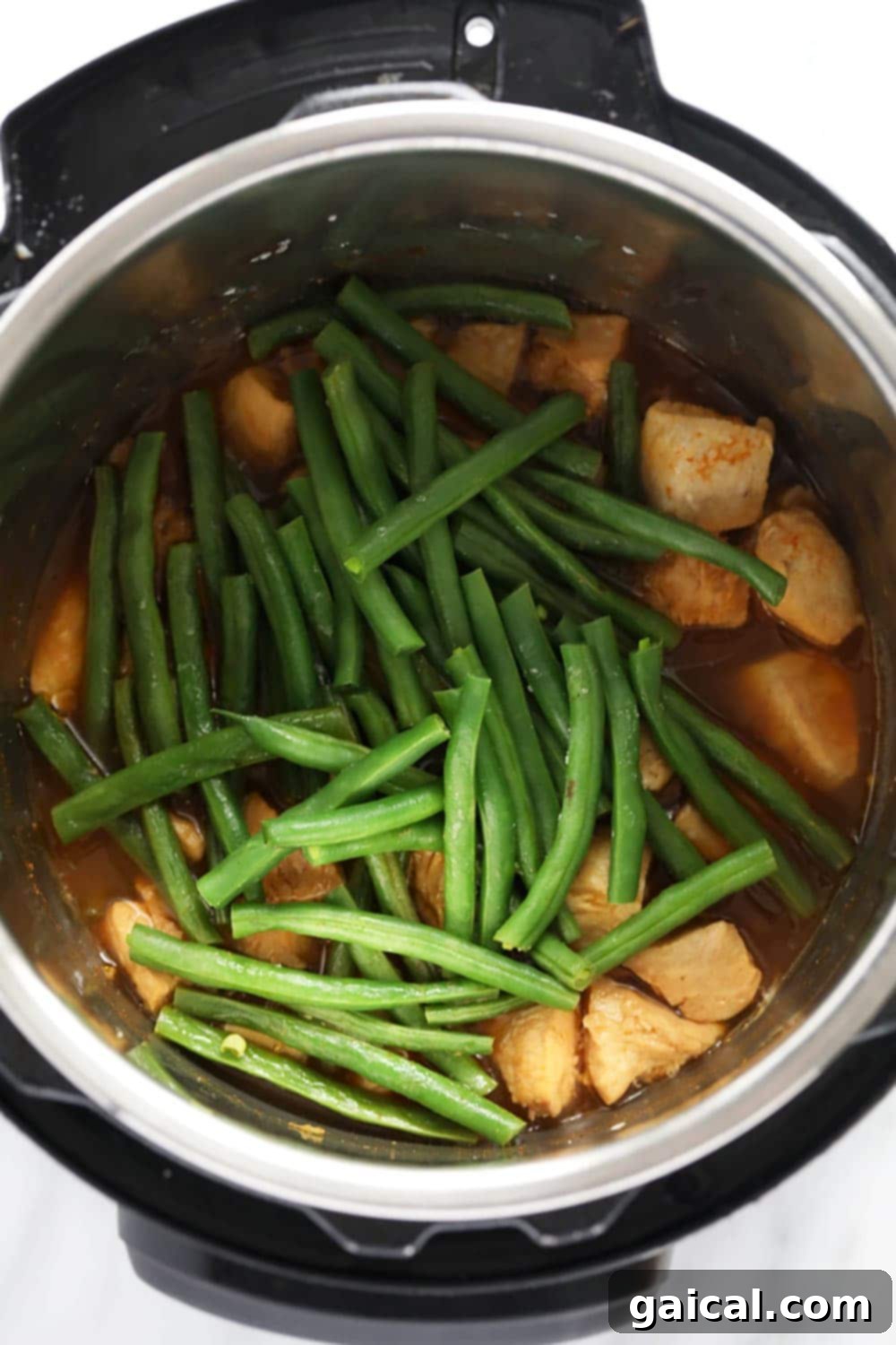 Cooked chicken and green beans nestled in the Instant Pot, ready for sauce thickening.