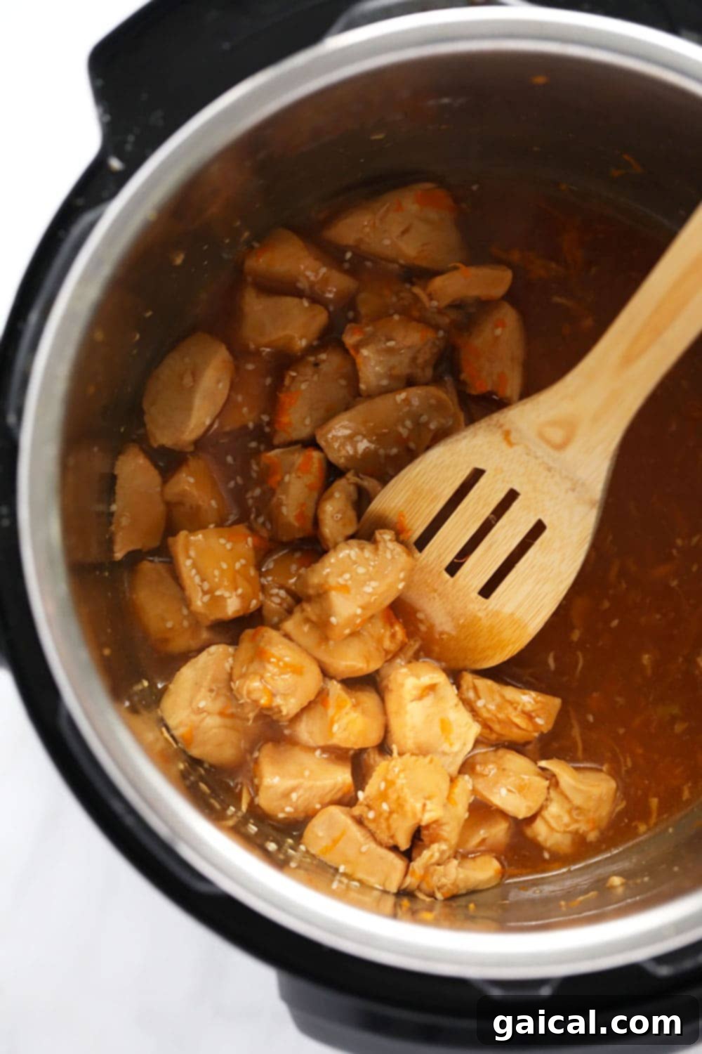 Instant Pot Orange Chicken coated in thick, glossy sauce, still in the Instant Pot.
