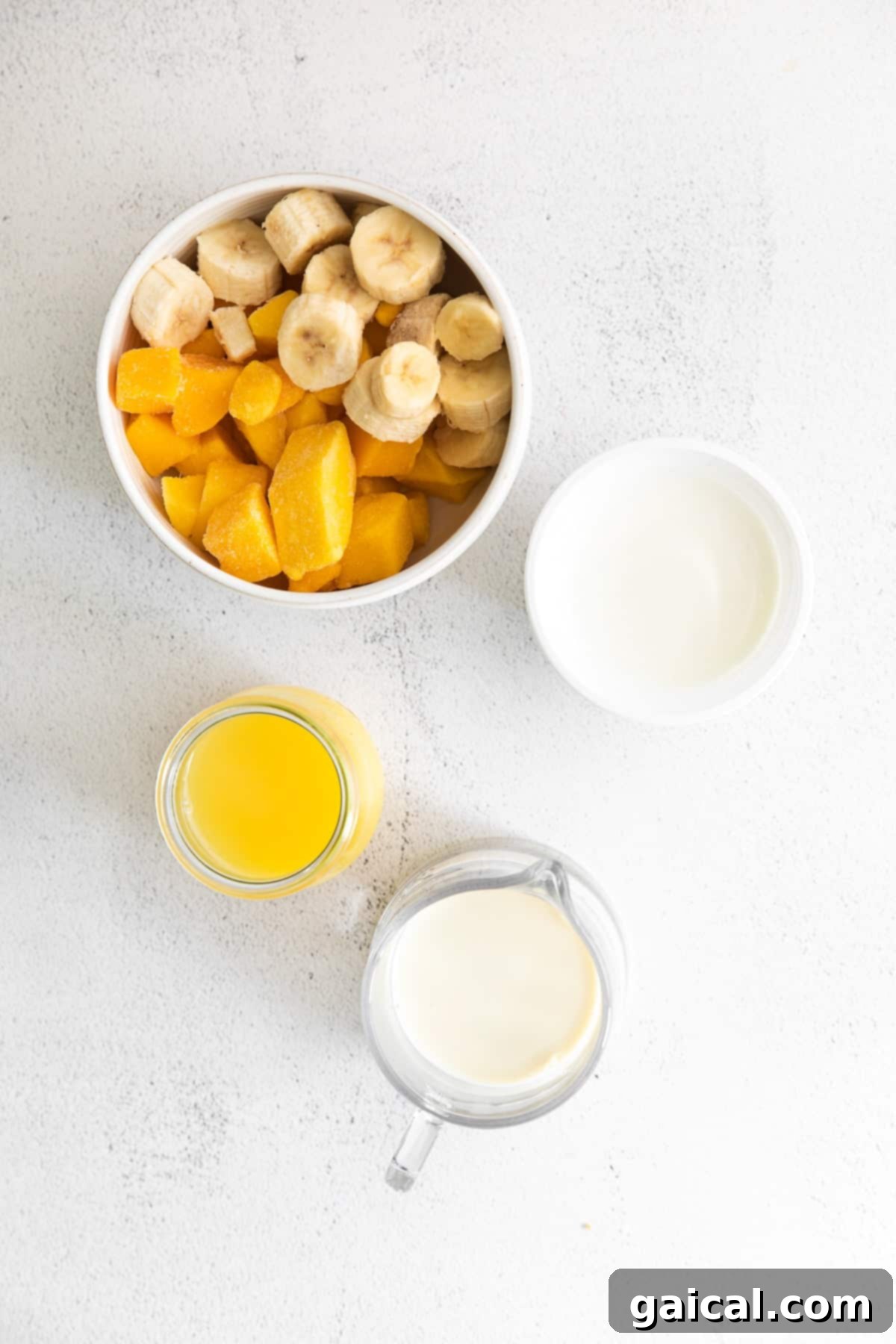 Tropical Mango Bliss 3 A selection of fresh and frozen ingredients, including mango, banana, and liquids, ready for blending into a delicious smoothie.