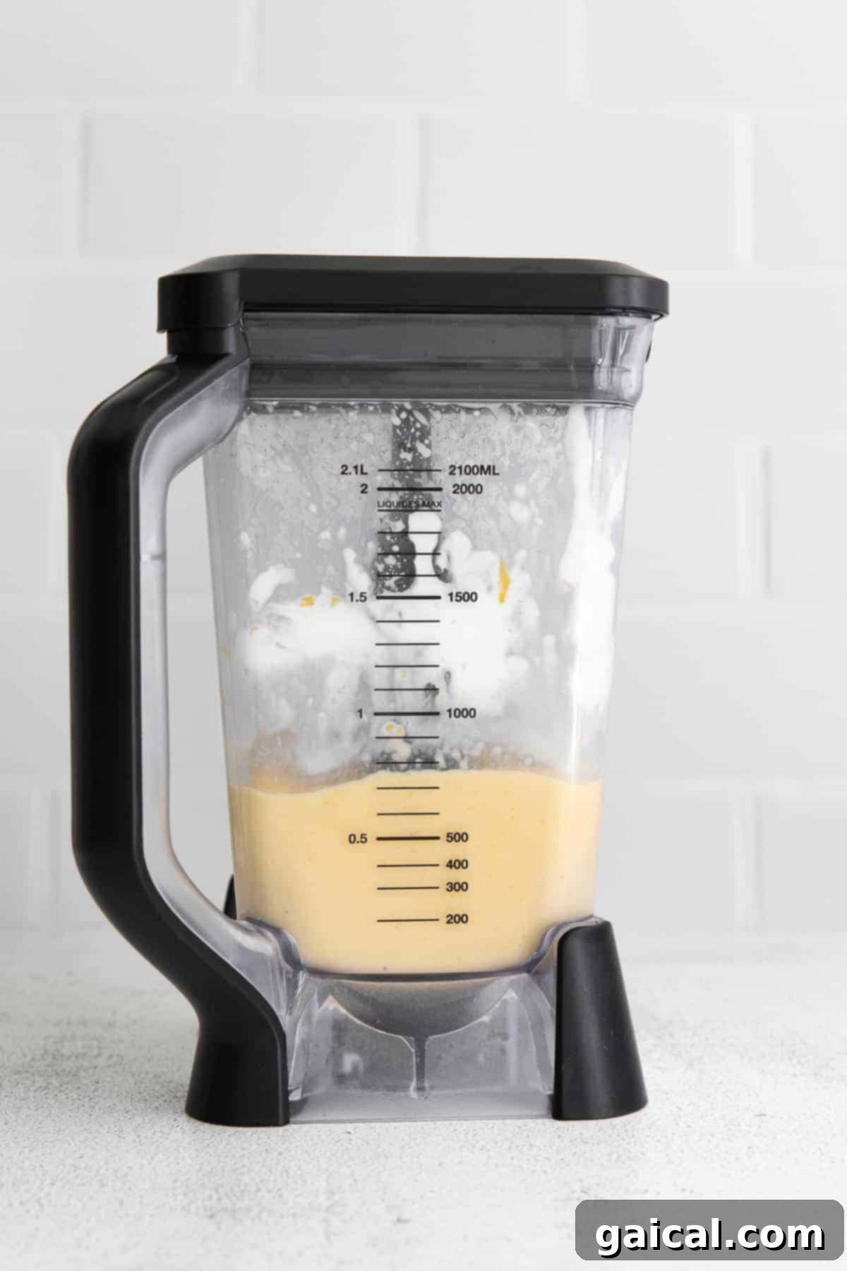 Tropical Mango Bliss 5 A close-up of a creamy mango smoothie being blended to perfection in a high-speed blender, showcasing its smooth texture.