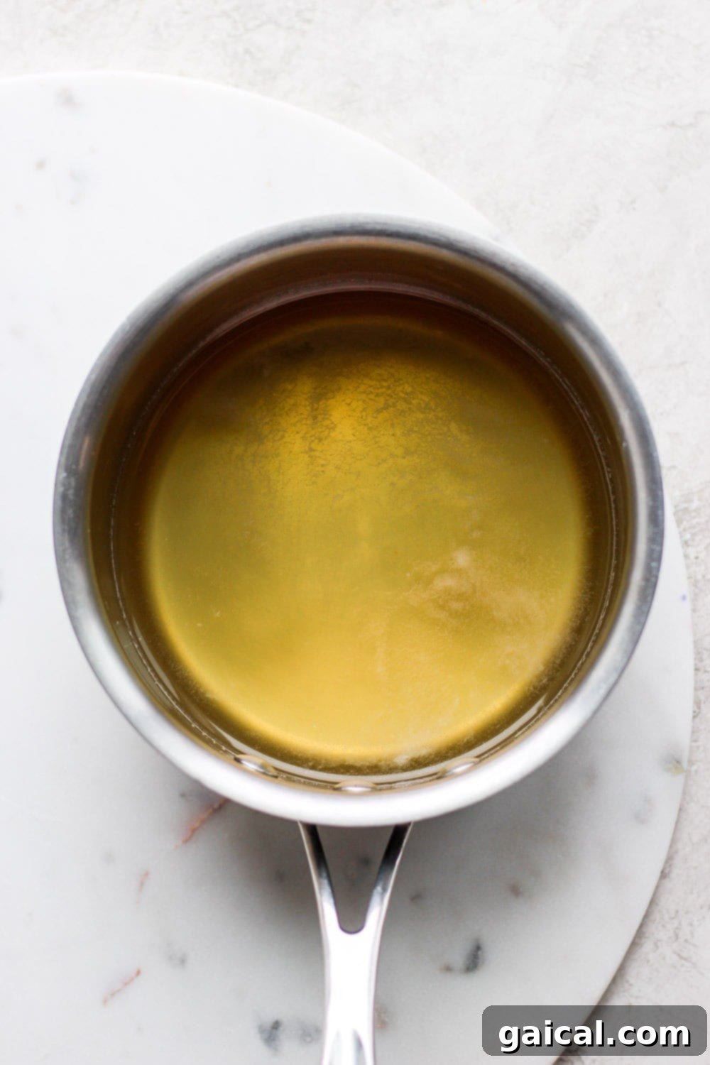 Simple syrup being prepared in a pot, a key component for sweetening cocktails. Simple Syrup simmering in a small pot on the stove