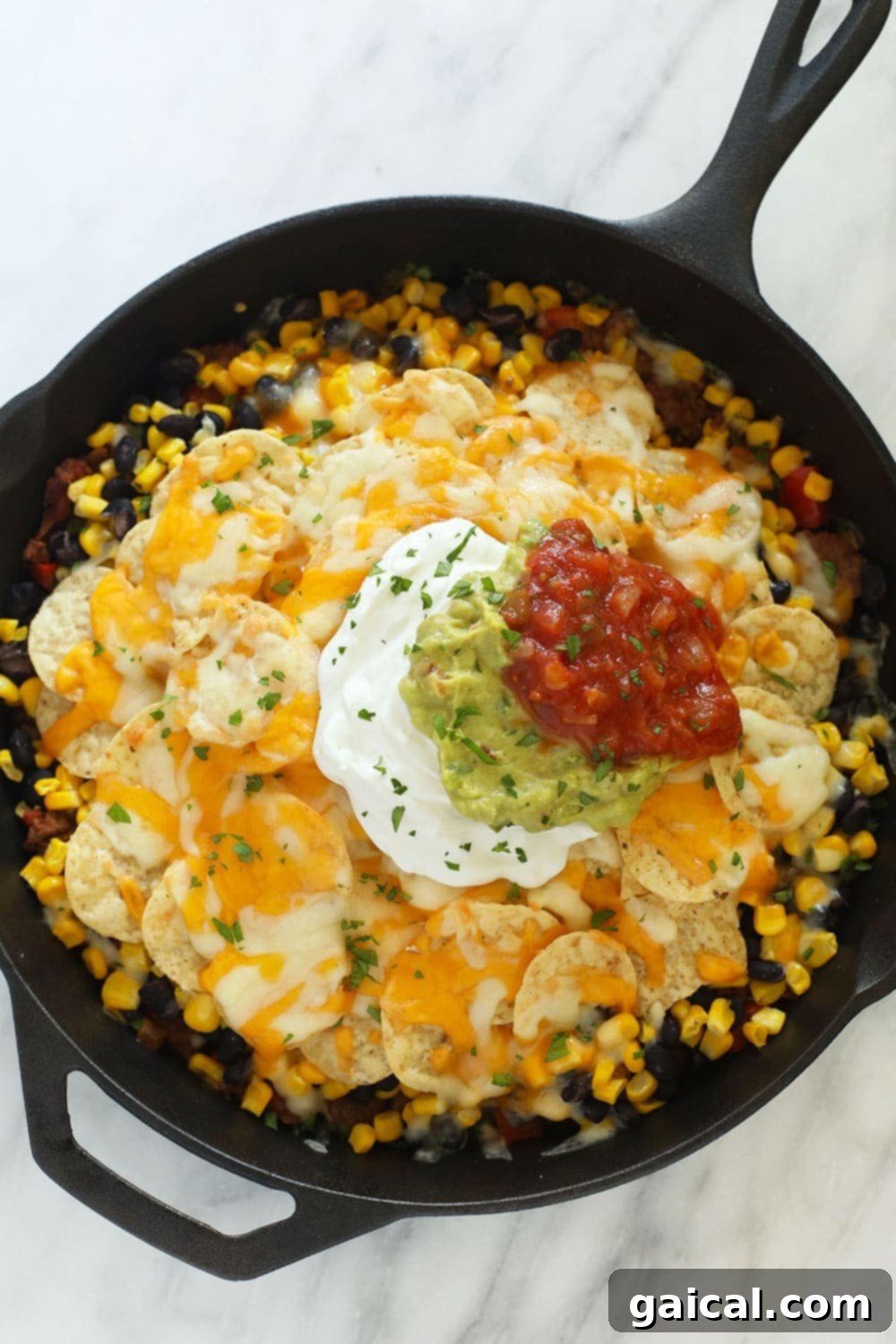 Simple Weeknight Taco Bake 2 Delicious easy taco casserole bubbling in a cast iron skillet, ready to serve.