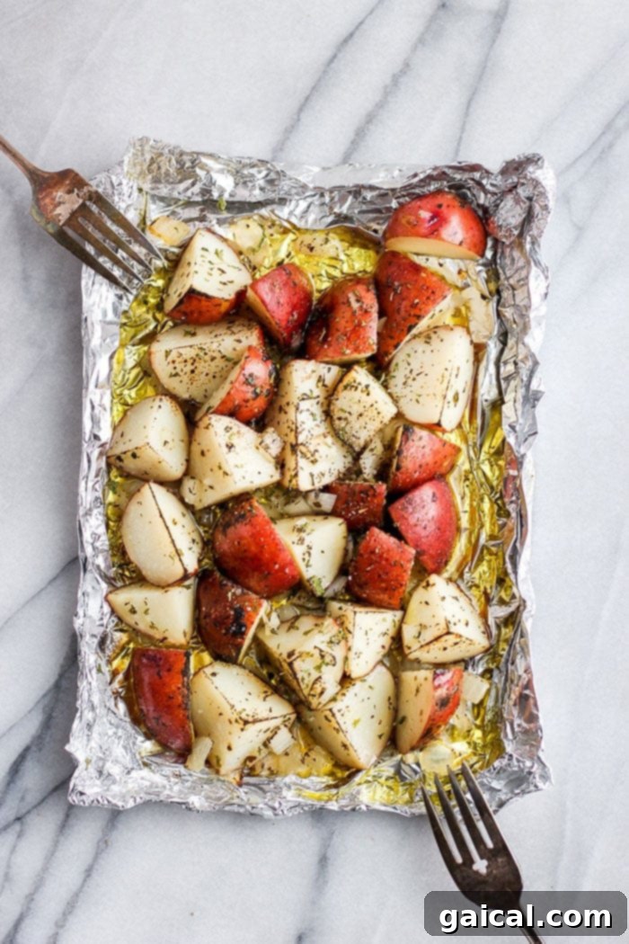 Grilled red potatoes in foil, golden brown and perfectly cooked, resting on a piece of aluminum foil