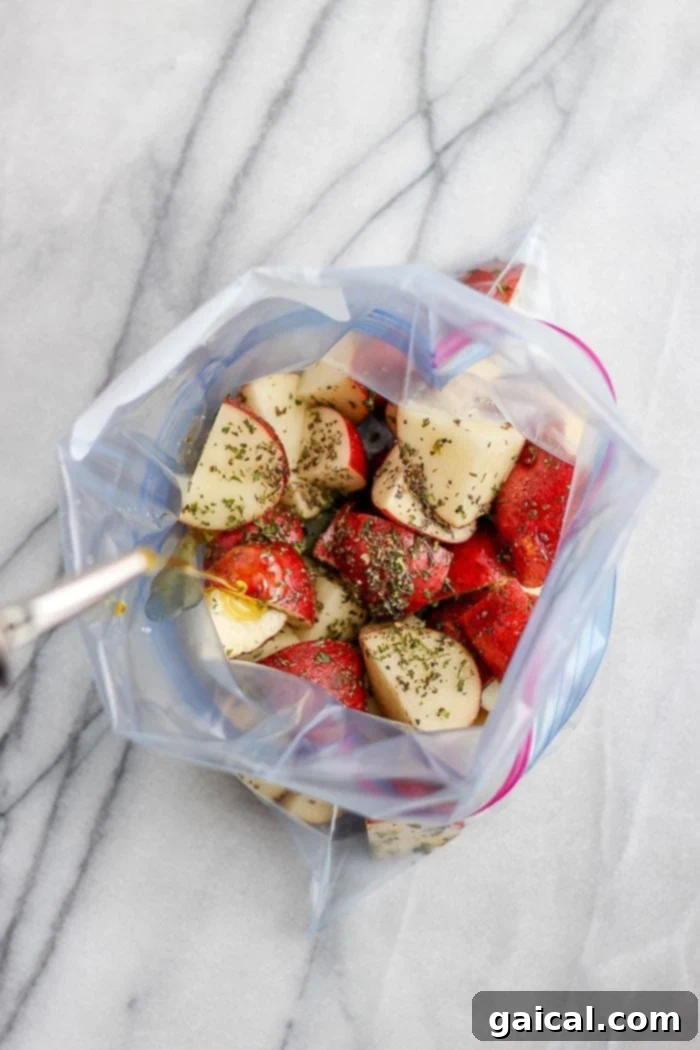 Red potatoes and spices being mixed in a plastic bag with olive oil