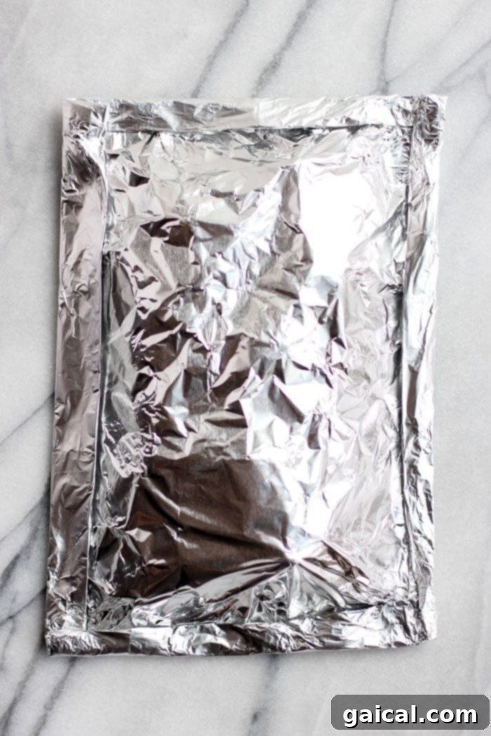 A securely sealed foil pack filled with seasoned potatoes, ready for grilling