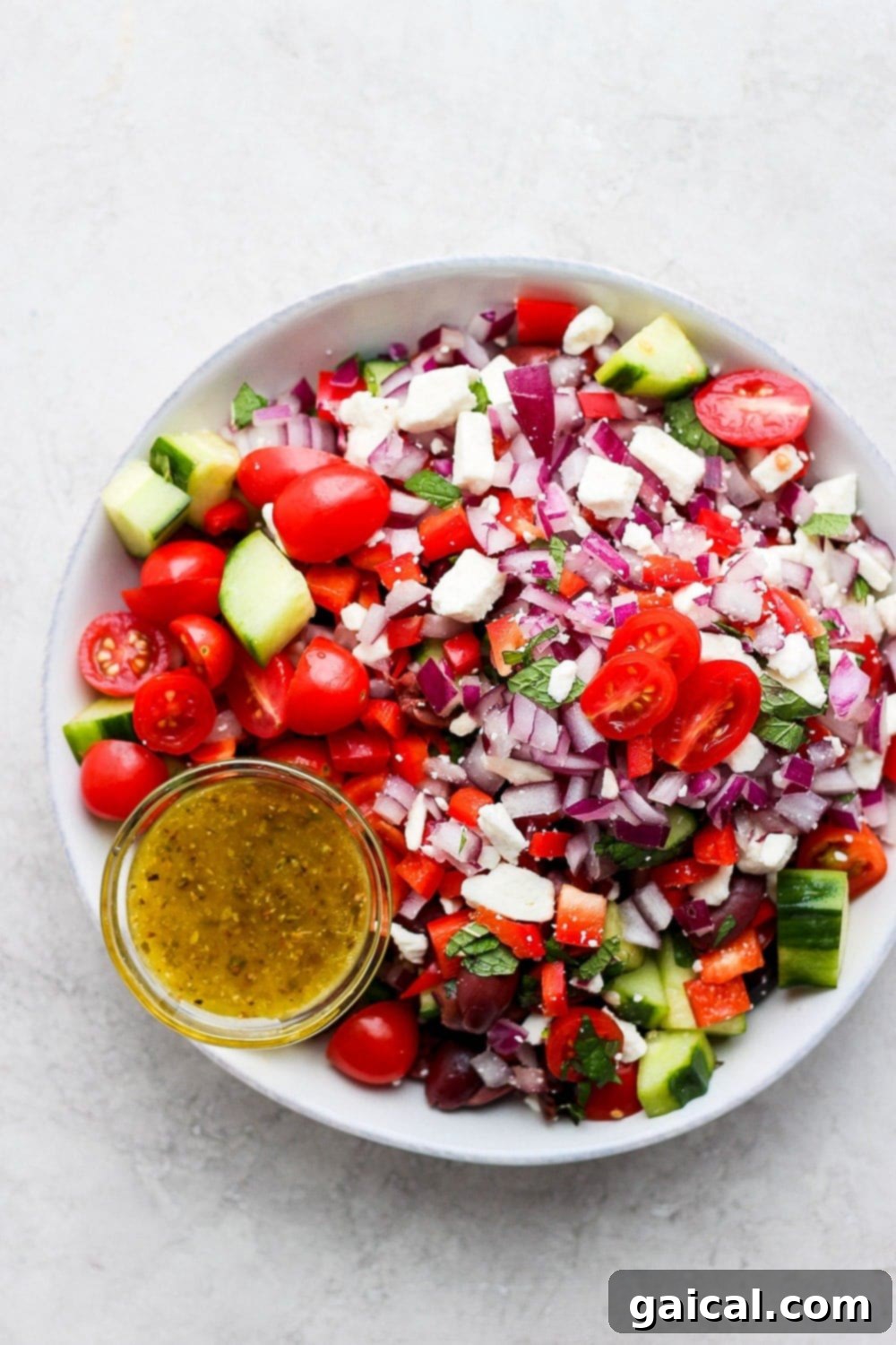 Vibrant Greek salad in a large wooden bowl, showcasing cherry tomatoes, cucumber, red onion, and feta cheese. The salad is a perfect medley of fresh ingredients.
