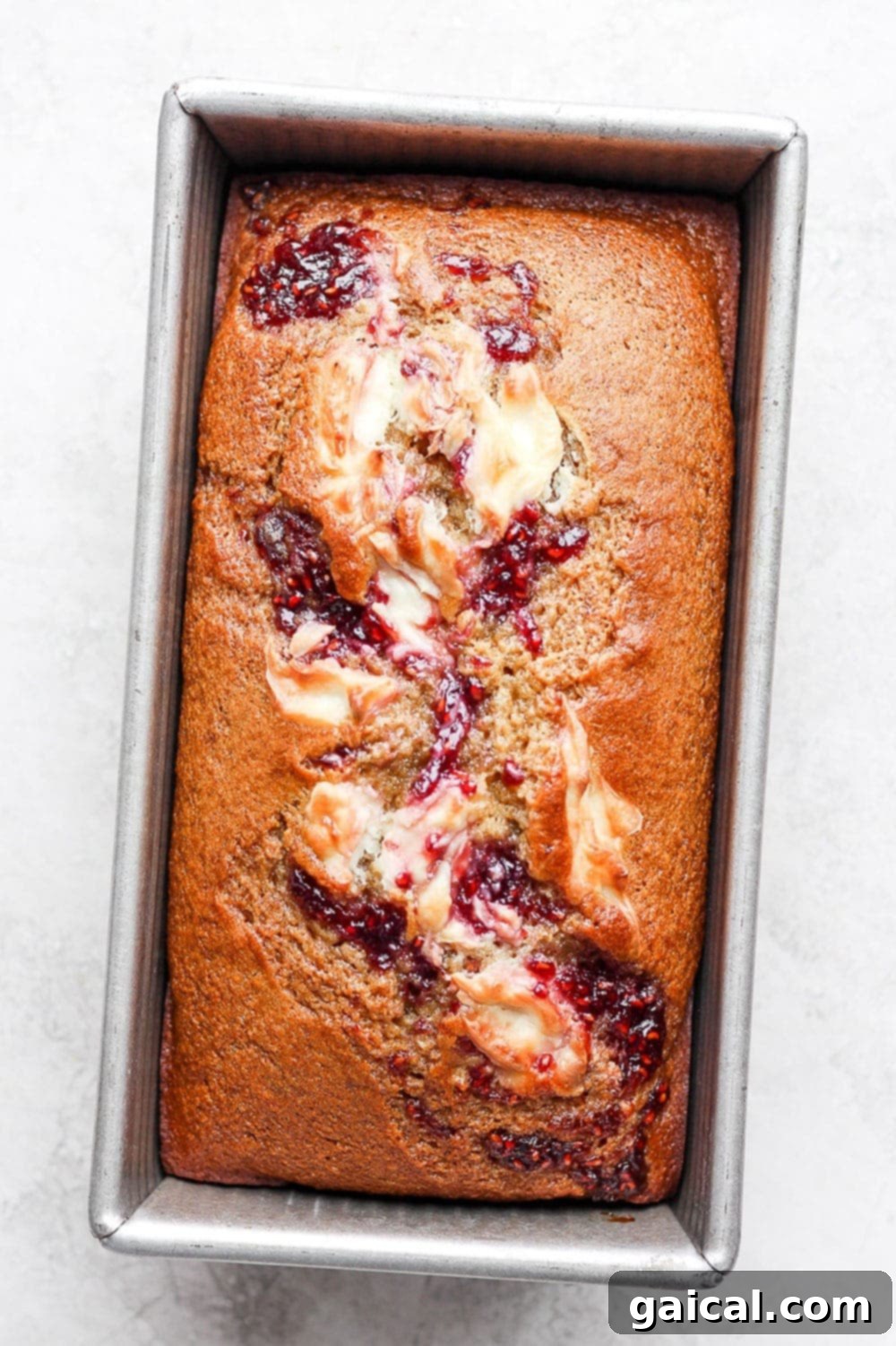 Freshly baked lemon bread with a raspberry cream cheese swirl in the loaf pan