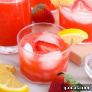 Ruby Red Strawberry Vodka Lemonade 3 A close-up image of a vibrant glass of strawberry vodka lemonade, garnished with fresh strawberries and a lemon slice.