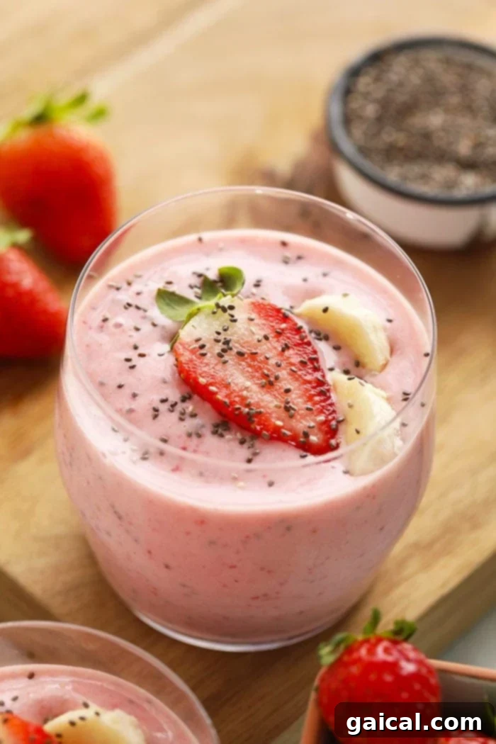 Vibrant pink, creamy strawberry chia seed smoothie in a glass, garnished with fresh strawberries, ready to be enjoyed.