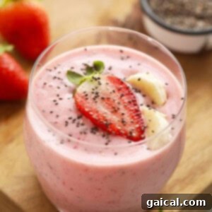 A beautiful bowl of strawberry smoothie, topped with fresh chia seeds and whole strawberries, ready to be eaten.