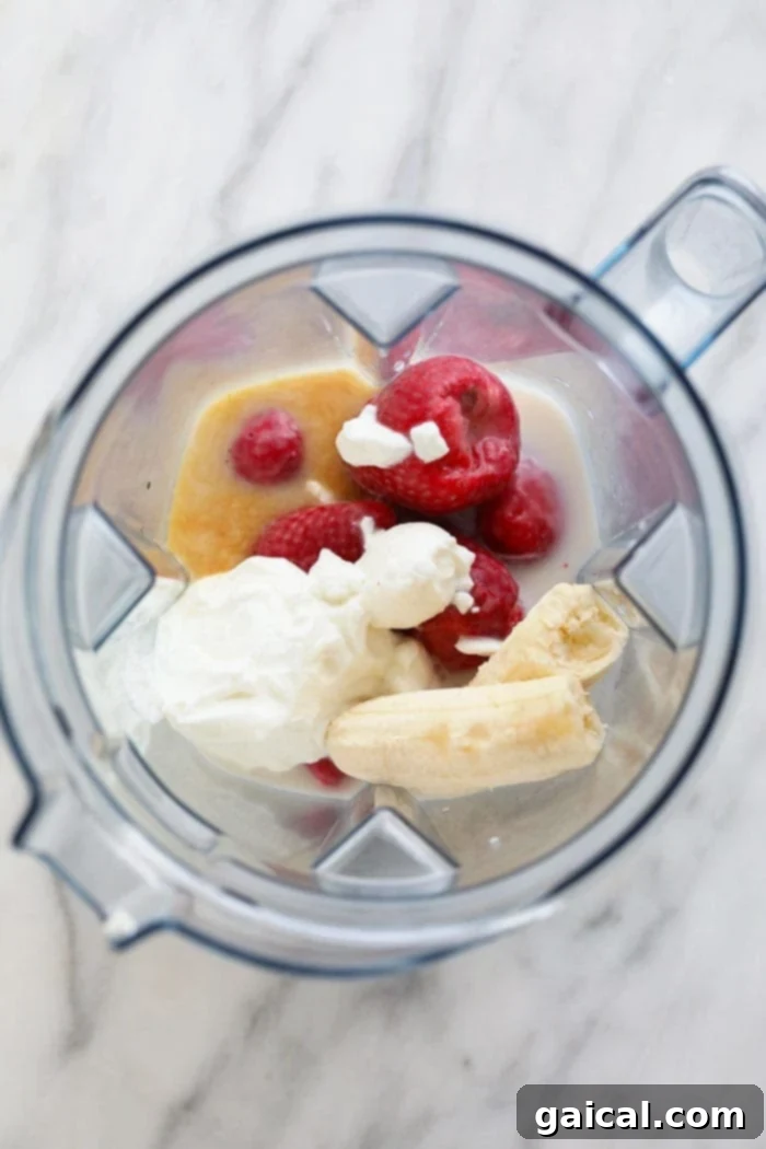 All ingredients for a strawberry chia seed smoothie meticulously placed within a Vitamix blender, ready for blending.