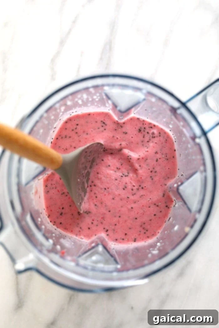 A creamy strawberry chia seed smoothie actively blending in a high-speed Vitamix blender, showcasing its smooth texture.