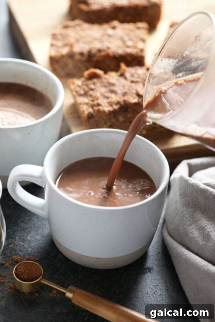 Comforting Vegan Chai Hot Chocolate 5 Vegan chai hot chocolate being poured from a saucepan into a mug