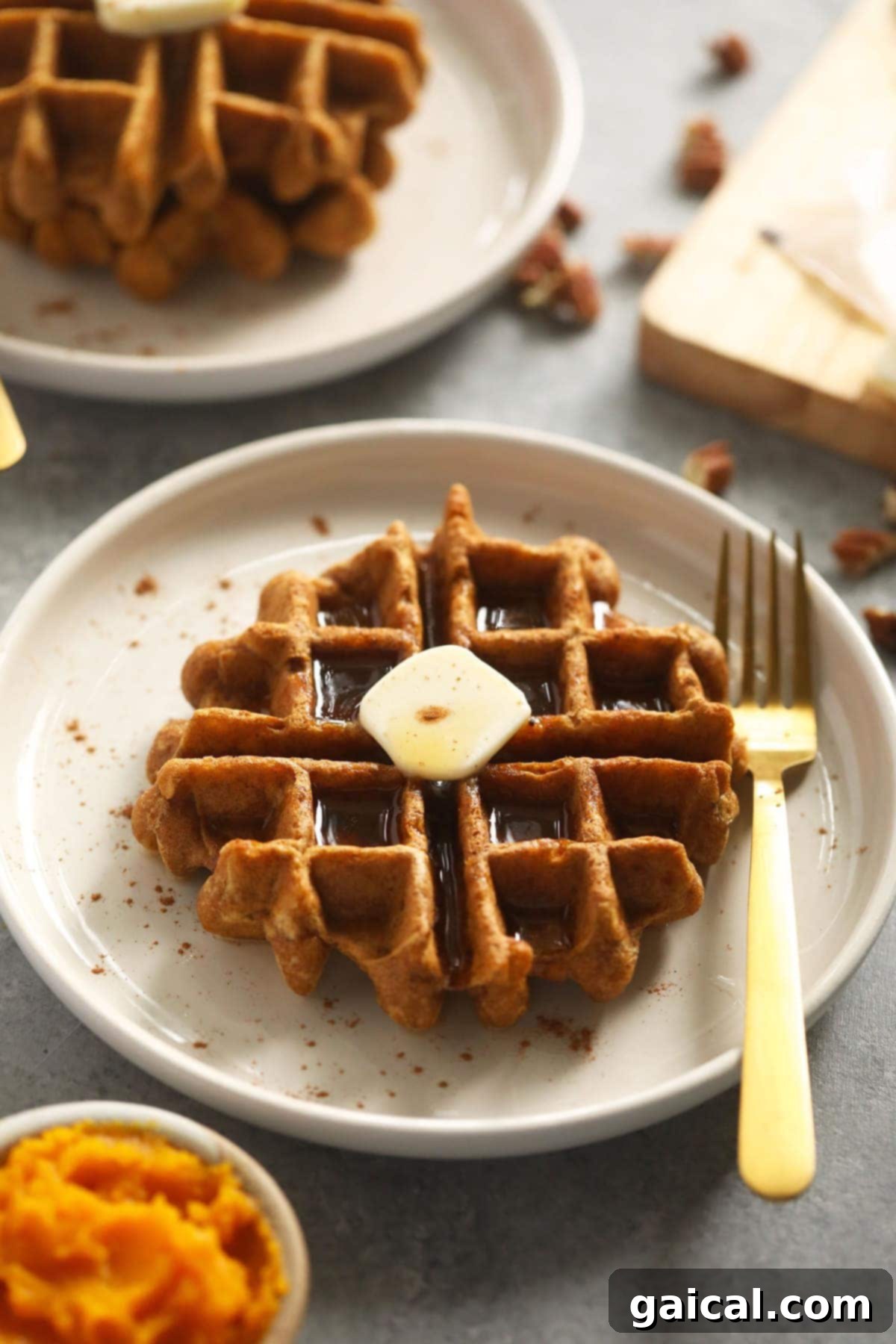 Got pumpkin? Make this delicious pumpkin gluten free waffles recipe! It's made with simple ingredients and pumpkin pie spice. A perfectly golden gluten-free pumpkin waffle on a white plate, ready to be enjoyed.