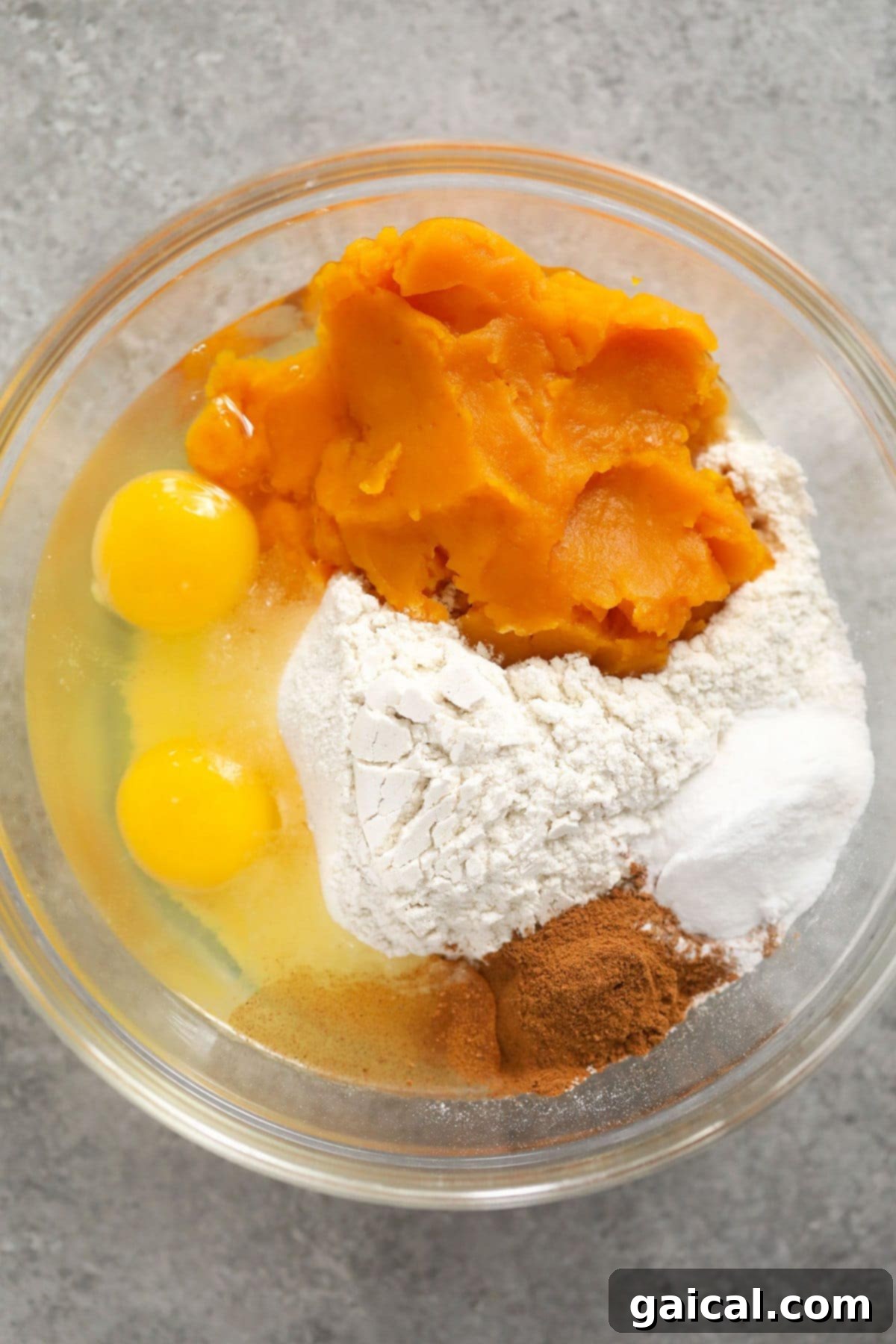 Got pumpkin? Make this delicious pumpkin gluten free waffles recipe! It's made with simple ingredients and pumpkin pie spice. Close-up of golden pumpkin waffle batter in a large mixing bowl, ready for the waffle iron.