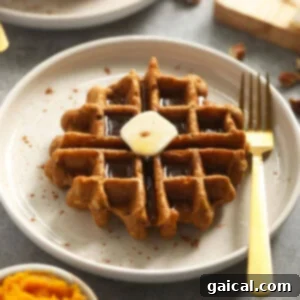 A delicious gluten-free pumpkin waffle topped with melted butter on a plate, ready to be served.