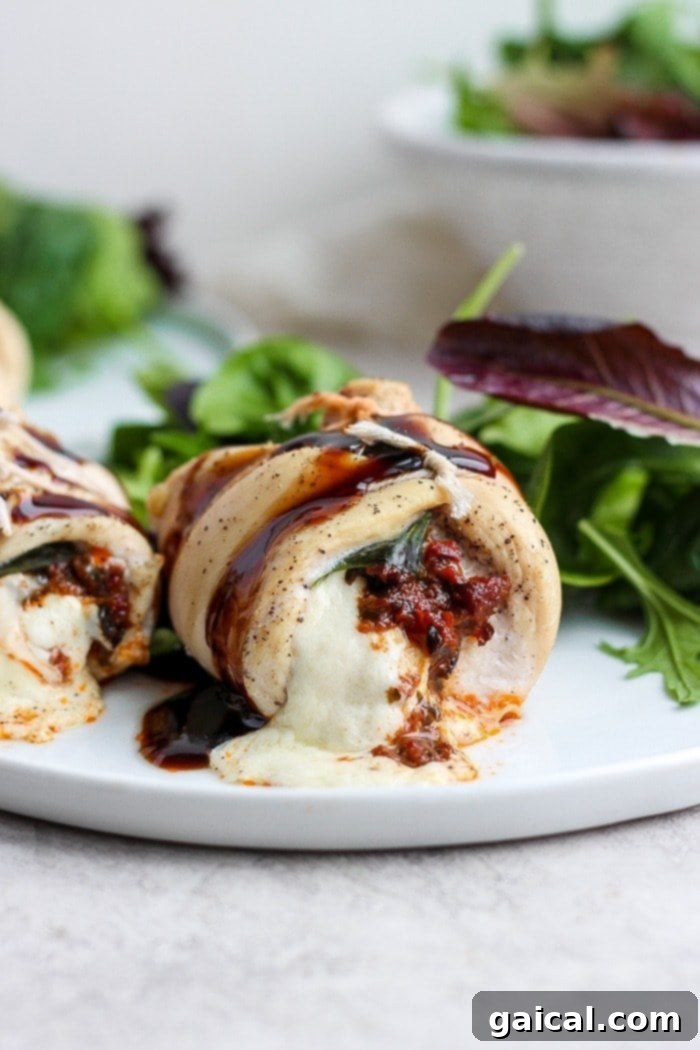This Caprese Stuffed Chicken Breast Recipe is an easy, healthy dinner that will wow your dinner guests. With only a few ingredients and easy step-by-step instructions, you'll have this delicious dinner ready in under 60 minutes. Enjoy! Stuffed chicken breast on a plate, garnished with fresh basil and balsamic glaze.