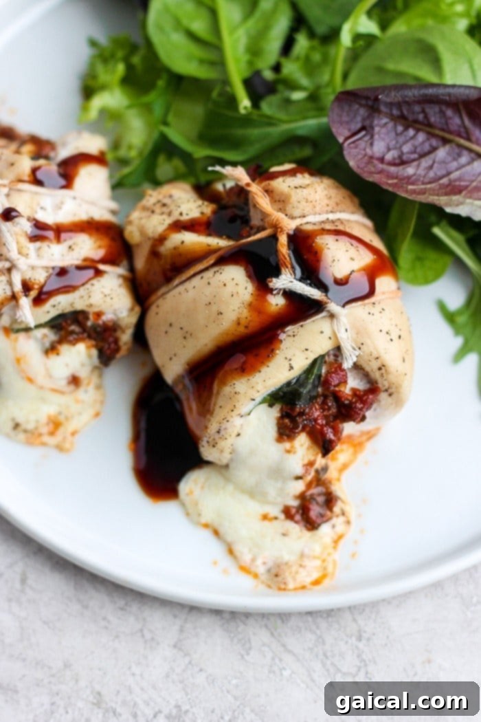 This Caprese Stuffed Chicken Breast Recipe is an easy, healthy dinner that will wow your dinner guests. With only a few ingredients and easy step-by-step instructions, you'll have this delicious dinner ready in under 60 minutes. Enjoy! Caprese stuffed chicken breast served on a white plate with fresh greens.