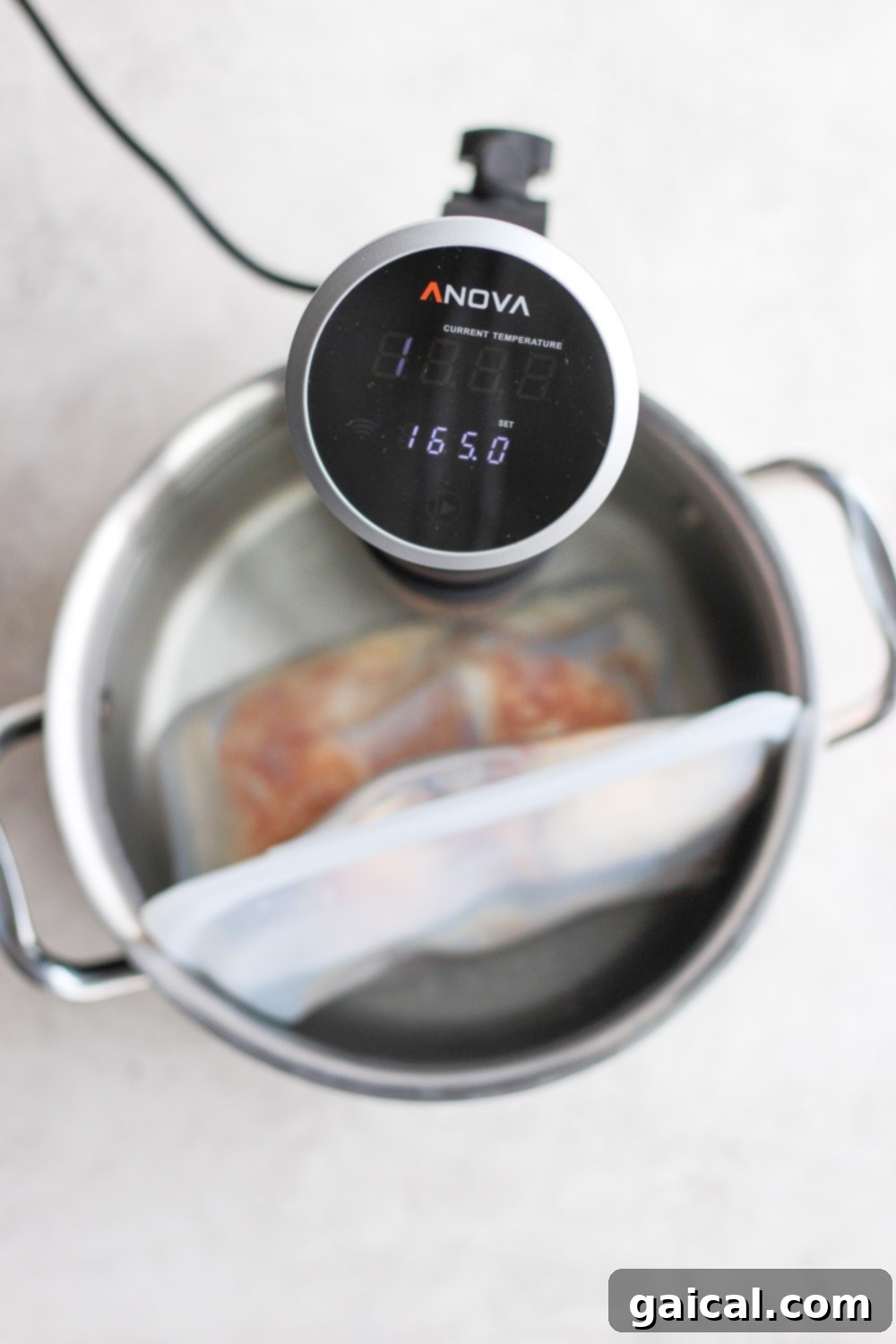 Sous vide machine maintaining a precise 165°F for chicken thighs. Sous vide immersion circulator set to 165 degrees Fahrenheit in a water bath
