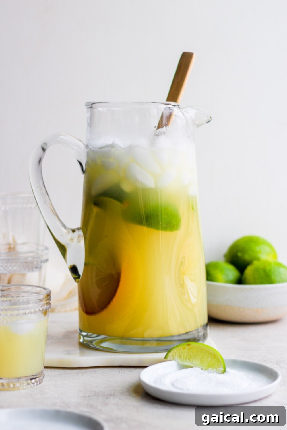 This is the BEST skinny margarita on the internet and it's made with 4 simple ingredients - tequila, fresh lime juice, ice, and honey/agave simple syrup! A pitcher filled with refreshing skinny margarita, garnished with lime slices.