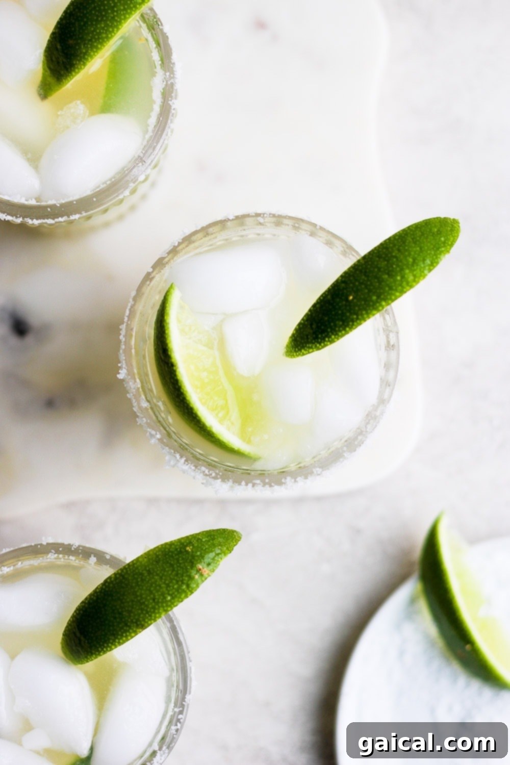 This is the BEST skinny margarita on the internet and it's made with 4 simple ingredients - tequila, fresh lime juice, ice, and your favorite all-natural sweetener! Two skinny margaritas in glasses, garnished with lime wedges and a salted rim.