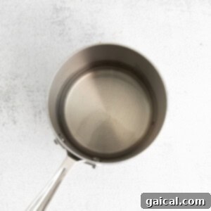 Guilt-Free Margarita 3 A stainless steel frying pan on a white background, containing water and honey for simple syrup.