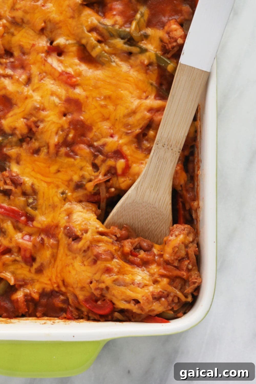 A serving spoon scooping out a portion of the hot chicken burrito bowl casserole from the baking dish