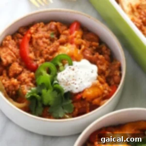 Close-up of a serving of Healthy Chicken Burrito Bowl Casserole in a bowl, with fresh toppings