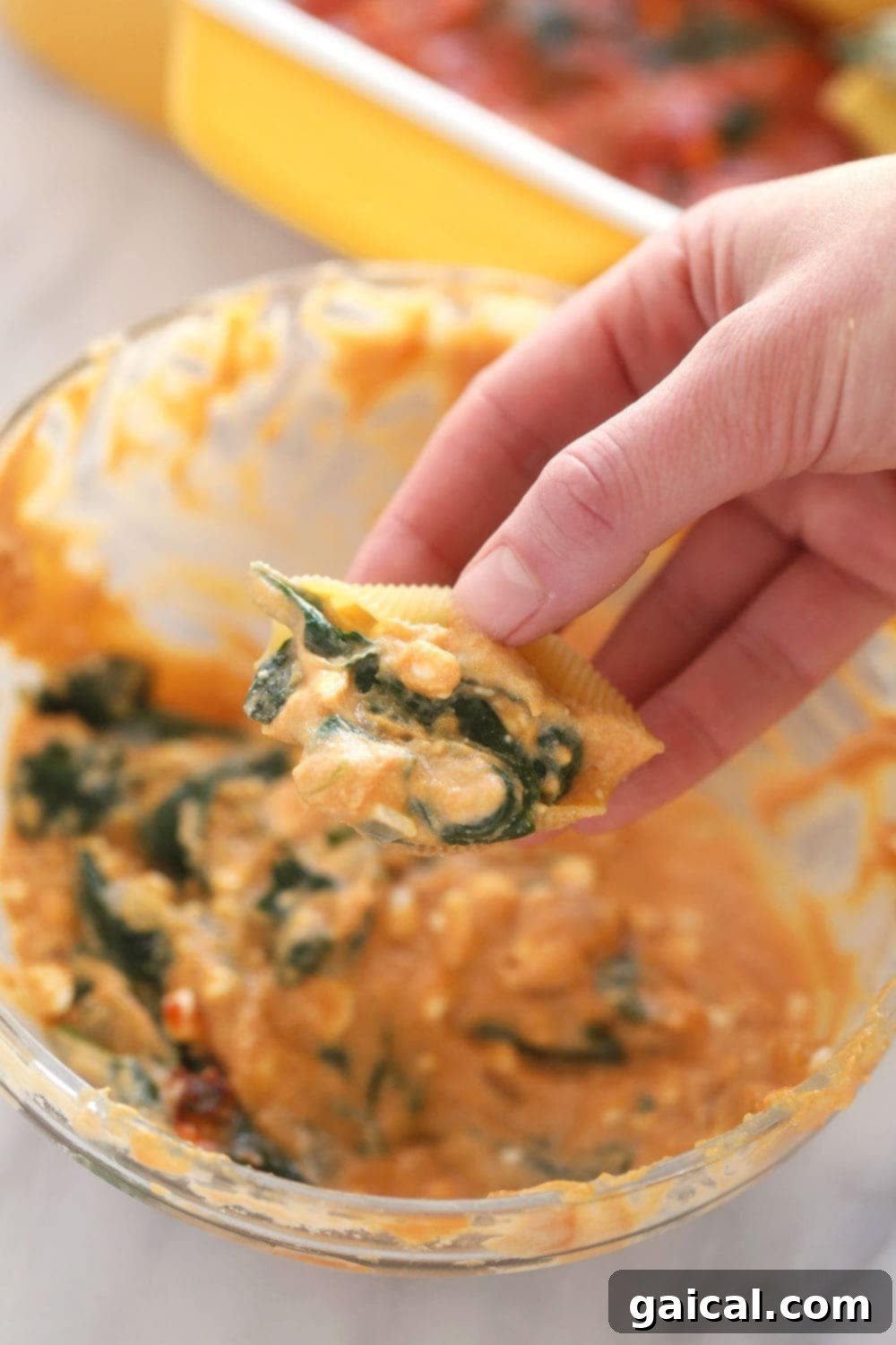 Creamy Sweet Potato, Spinach and Ricotta Stuffed Shells 4 Hands carefully stuffing uncooked jumbo pasta shells with the creamy sweet potato and spinach filling.