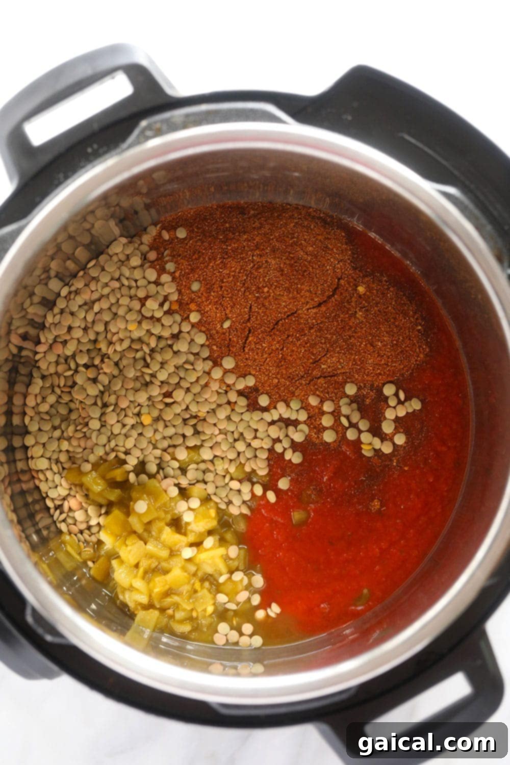 Raw Ingredients for Instant Pot Lentil Tacos The inside of an Instant Pot filled with uncooked lentils, vegetable broth, green chiles, tomato sauce, and taco seasoning, ready to be cooked into a delicious taco filling.