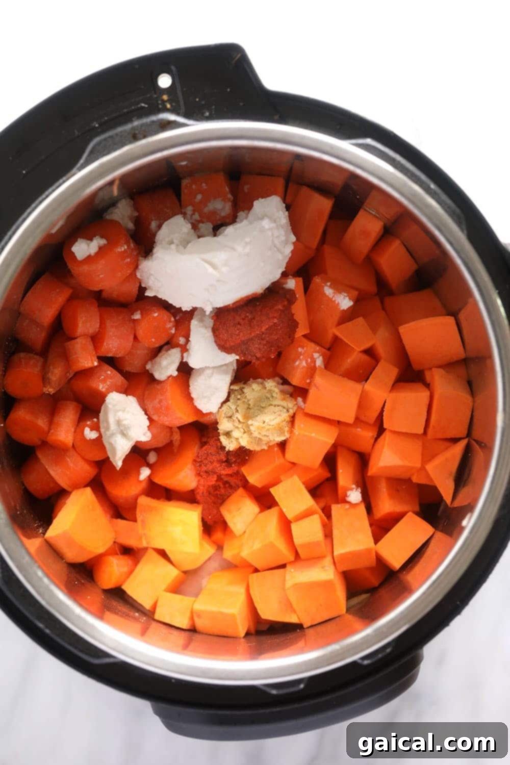 A close-up view of the raw ingredients for Instant Pot Sweet Potato Carrot Ginger Soup inside the Instant Pot, ready for cooking.