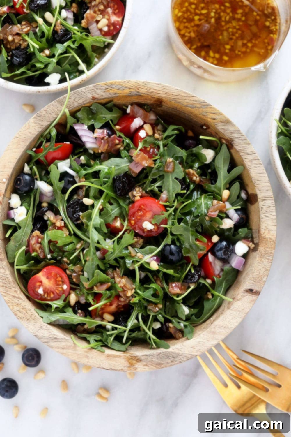 Rocket Salad with Lemon and Parmesan 2 A vibrant and colorful arugula salad in a large mixing bowl, showcasing a medley of fresh ingredients like blueberries, tomatoes, and pine nuts.