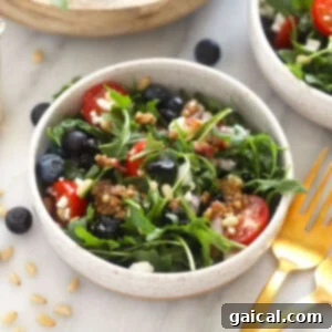 Rocket Salad with Lemon and Parmesan 3 A beautifully plated bowl of healthy arugula salad brimming with various colorful toppings, ready to be enjoyed.
