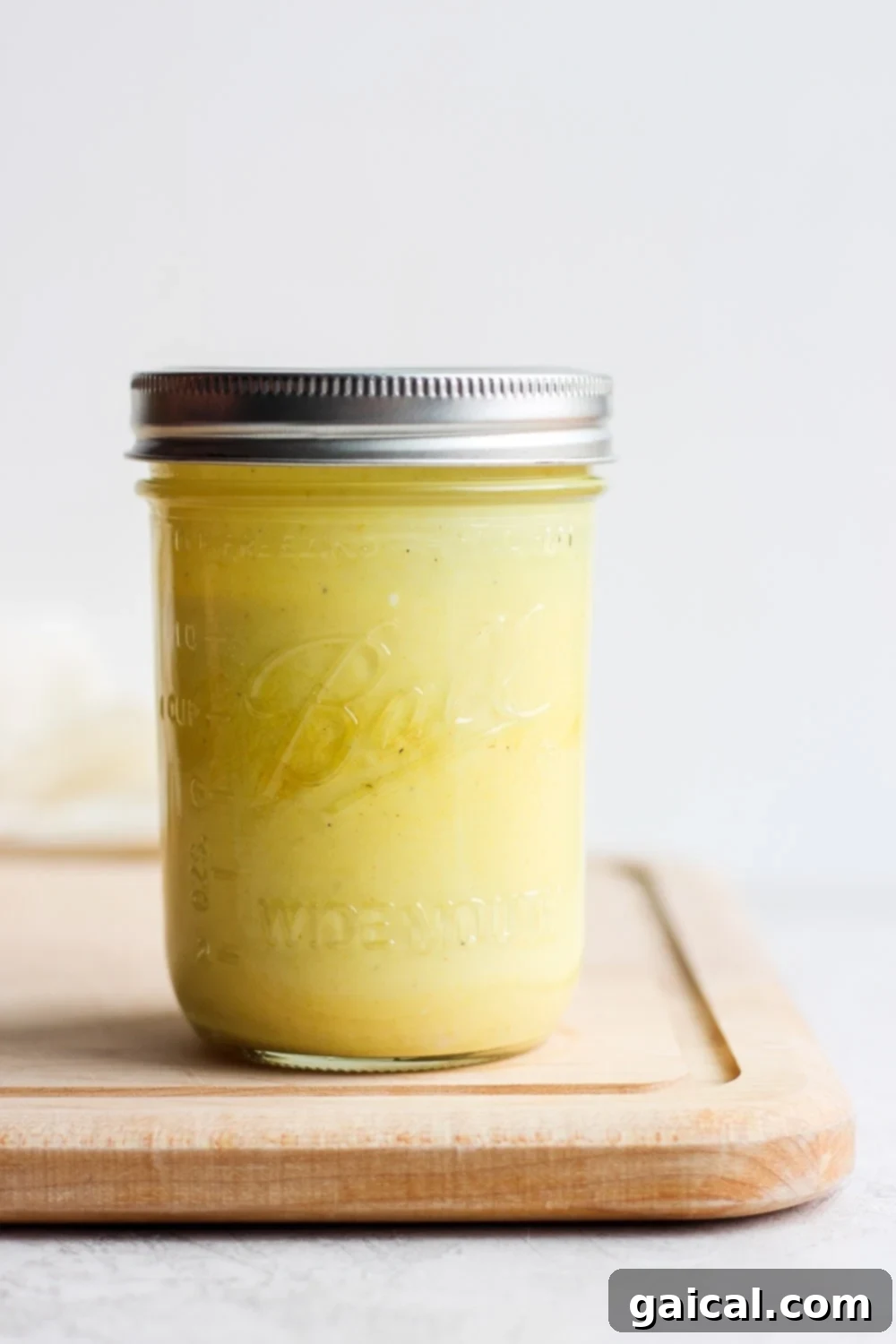 Effortless Honey Mustard Delight 2 Delicious honey mustard dressing in a glass jar on a wooden cutting board, ready to be served.