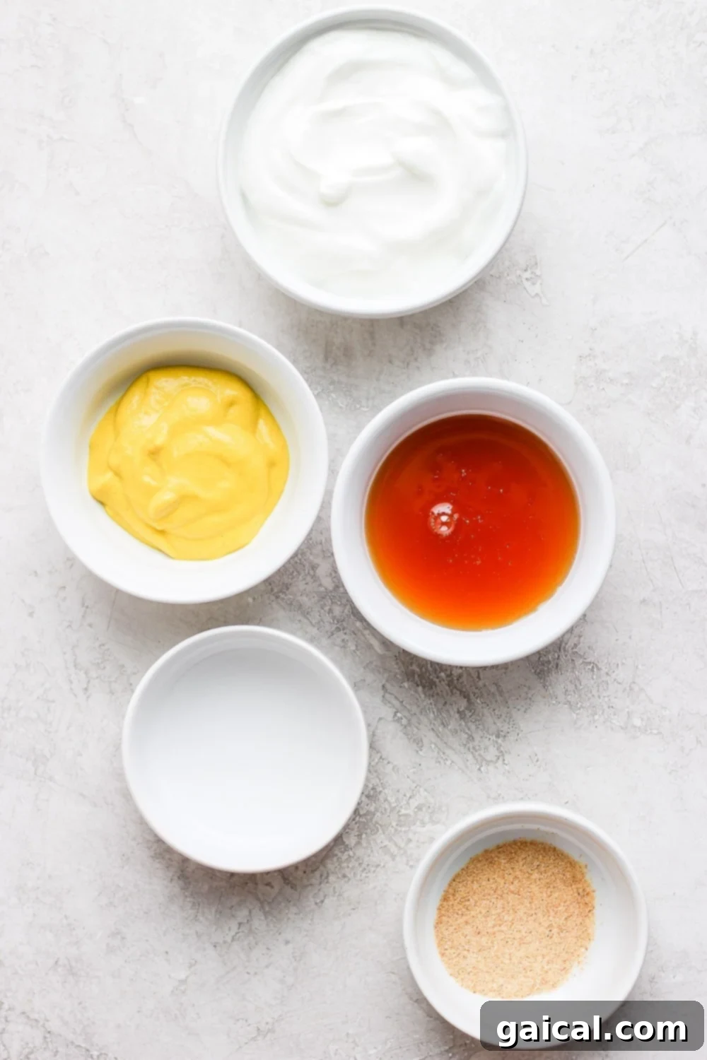 Effortless Honey Mustard Delight 3 Bowls of fresh ingredients for honey mustard dressing including Greek yogurt, honey, and yellow mustard.
