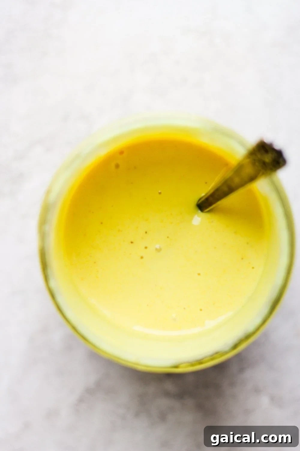 Effortless Honey Mustard Delight 6 Homemade honey mustard dressing in a jar with a spoon dipped in it, ready to be served.