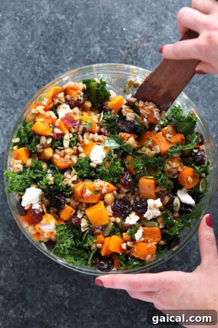 Stirring the Farro salad with kale and butternut squash in a large mixing bowl.