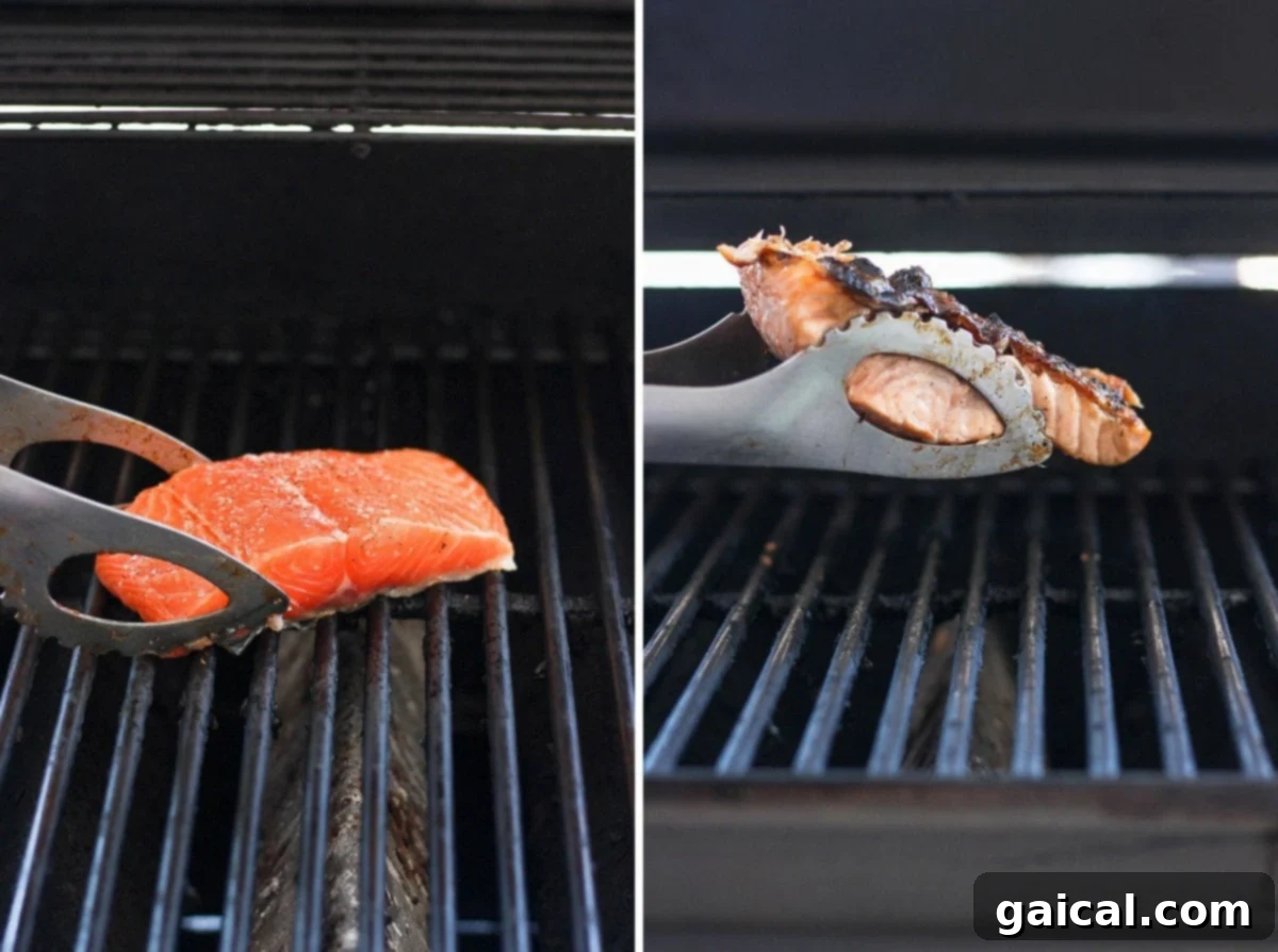A close-up shot of a salmon fillet sizzling on the hot grates of a gas grill, skin-side down, showing the grill marks beginning to form and the vibrant color of the fish.