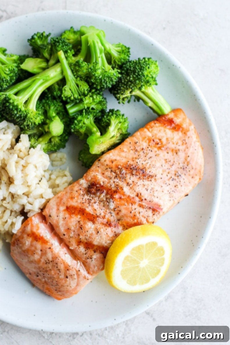 A close-up shot of a perfectly grilled and flaky salmon fillet, served beautifully on a plate with vibrant green broccoli and wholesome rice, highlighting a complete and healthy meal.