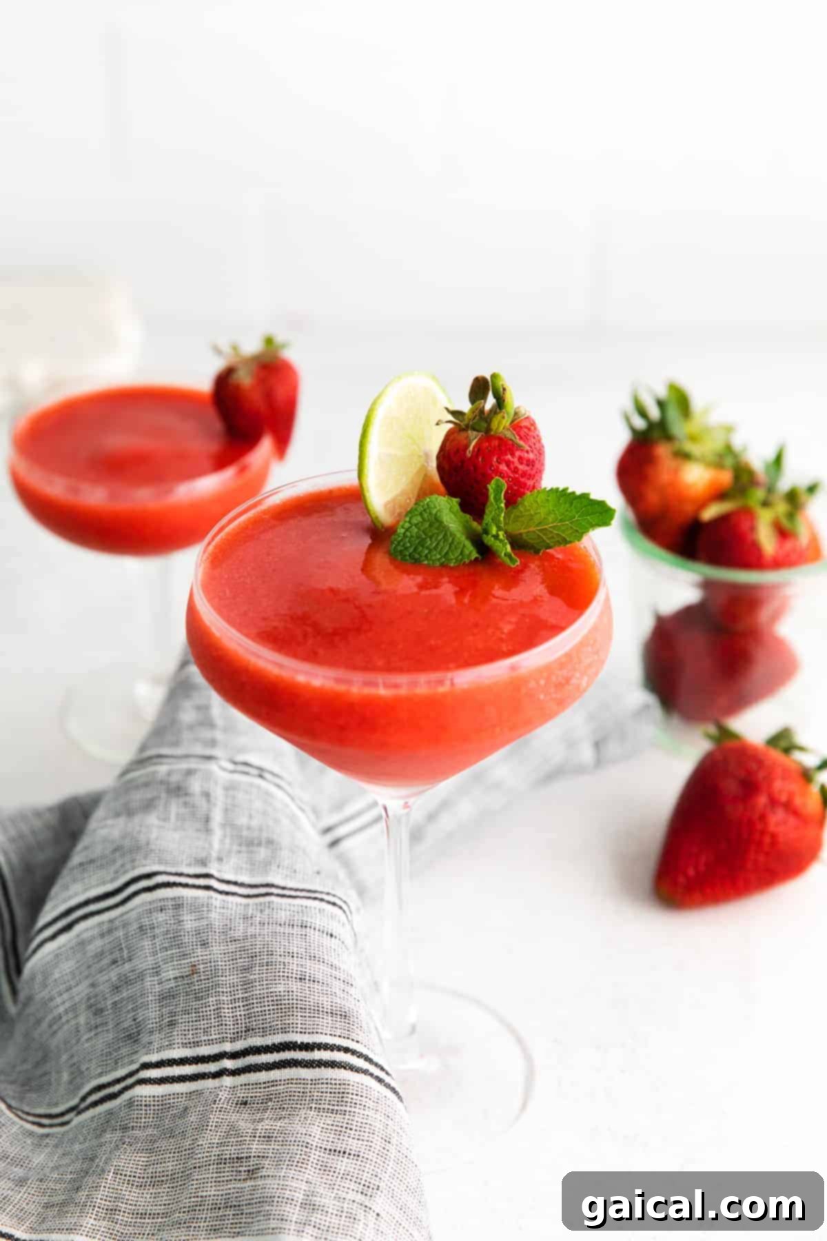Vibrant strawberry daiquiri garnished with fresh lime and mint, inviting a refreshing sip.