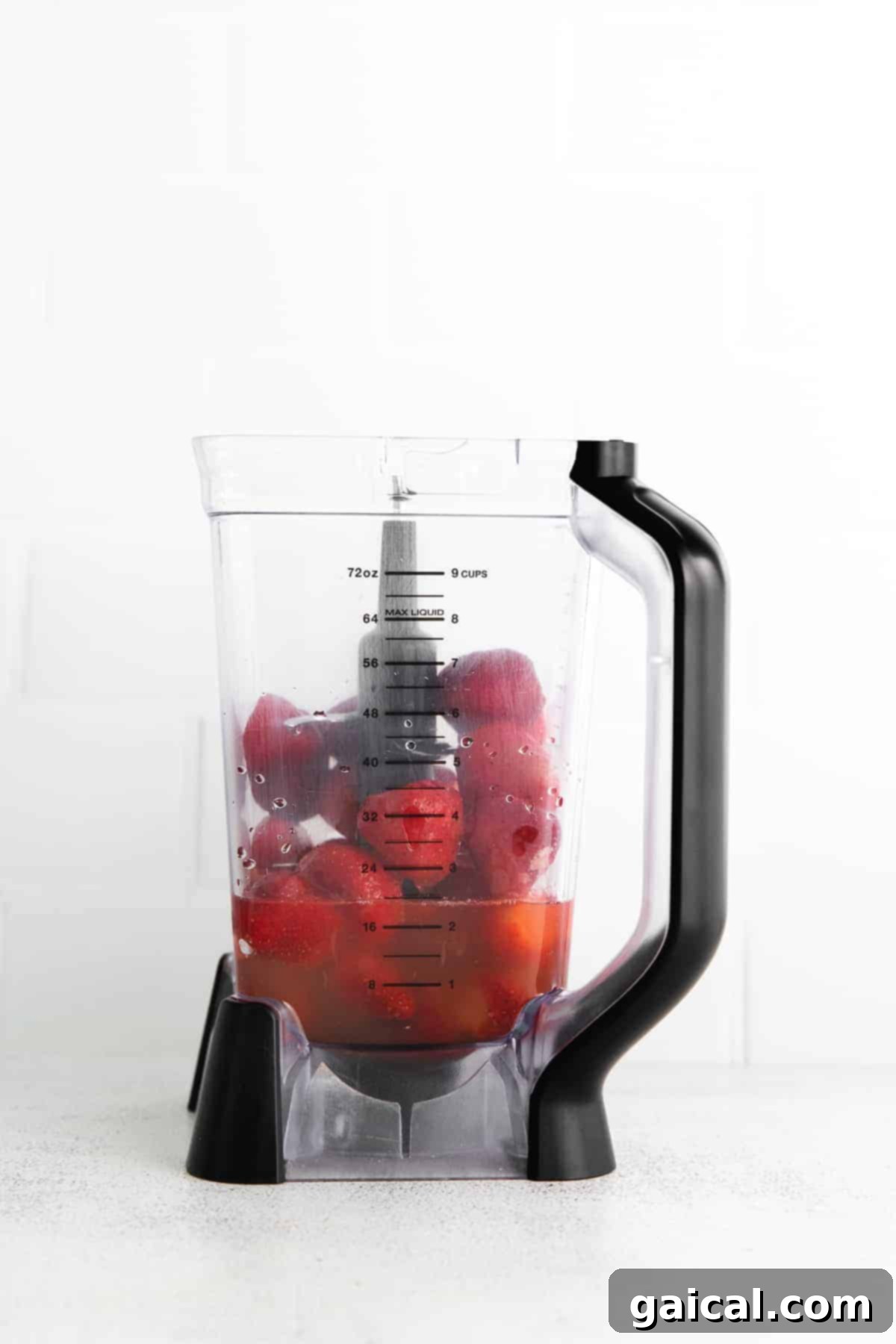 Frozen strawberries and white rum being poured into a high-speed blender, ready for mixing.