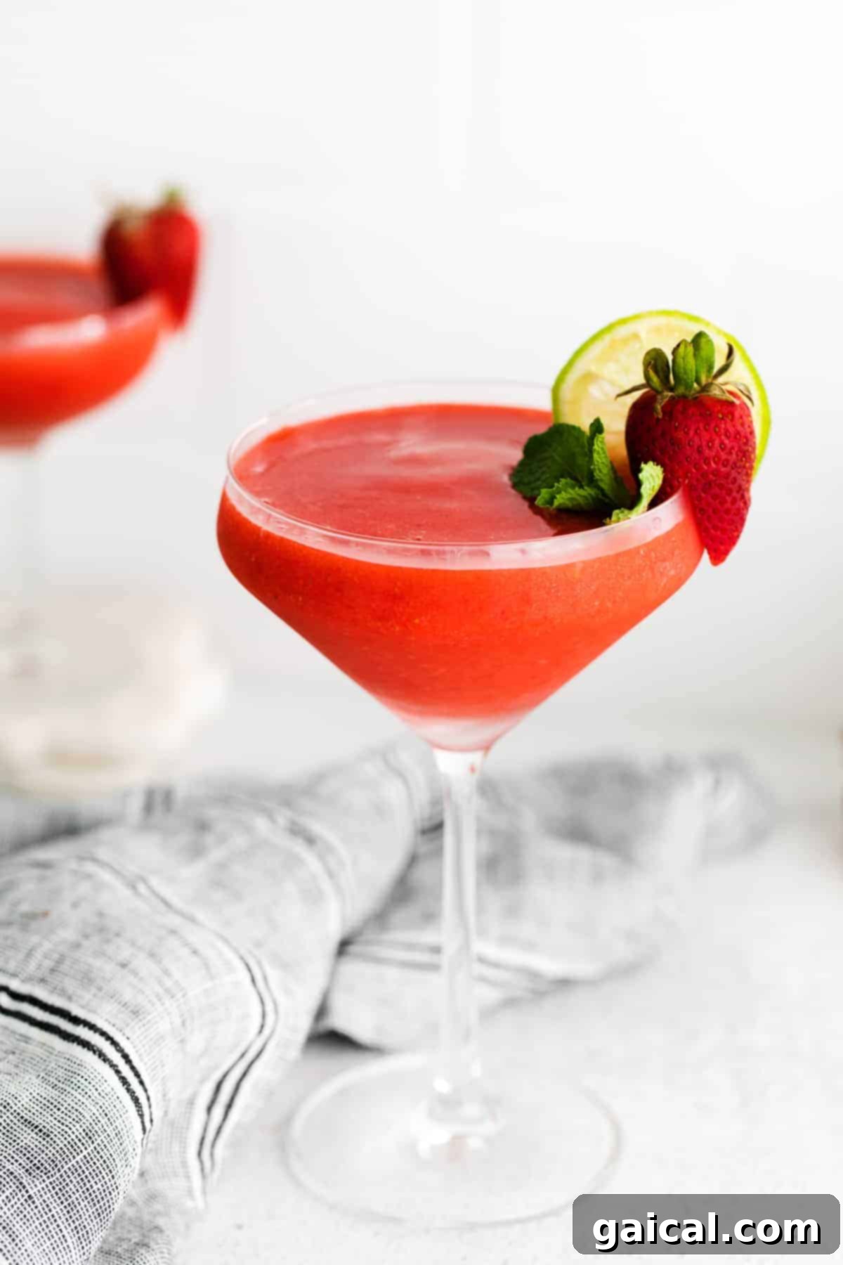 A refreshing strawberry daiquiri served in a classic cocktail glass, garnished with a fresh strawberry and lime.