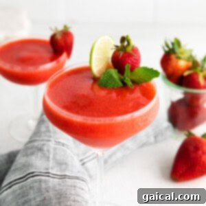 A stunning strawberry daiquiri cocktail in a glass, garnished with a fresh strawberry and lime.